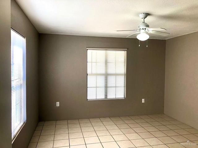 tiled spare room with ceiling fan and a healthy amount of sunlight