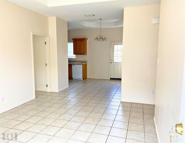 tiled empty room featuring a raised ceiling and a notable chandelier