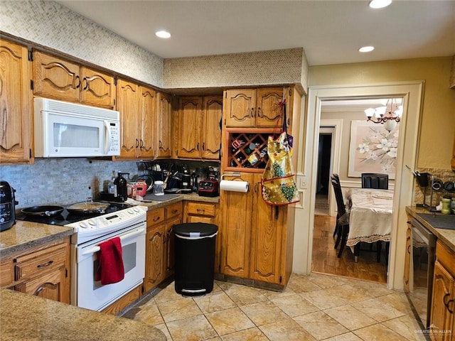 kitchen featuring brown cabinetry, decorative backsplash, white appliances, recessed lighting, and a chandelier