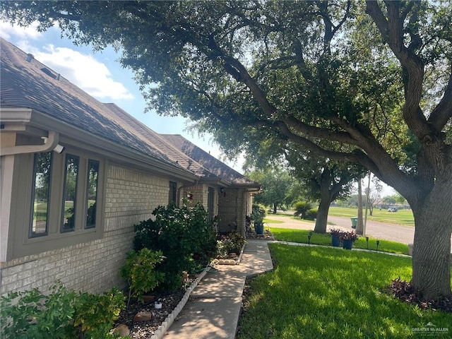 view of side of property featuring a lawn and brick siding