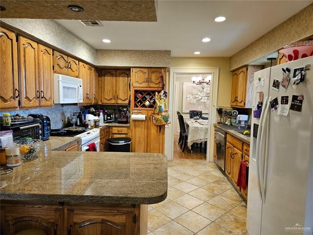 kitchen with brown cabinetry, decorative backsplash, a peninsula, white appliances, and light tile patterned floors