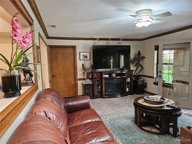 living room featuring baseboards, ornamental molding, a ceiling fan, and visible vents