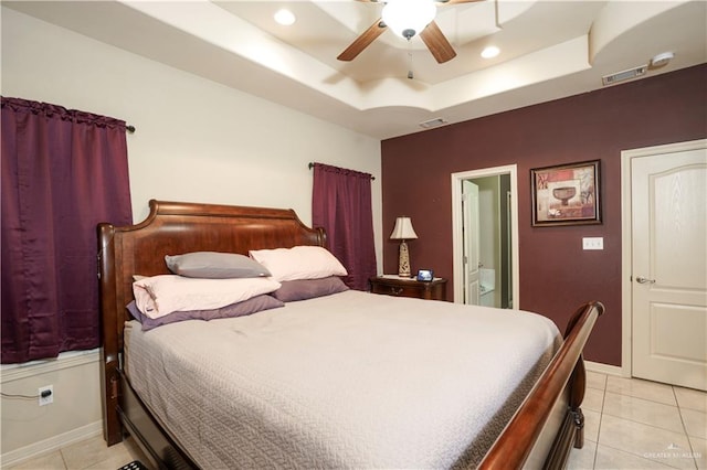 tiled bedroom featuring ceiling fan, connected bathroom, and a tray ceiling