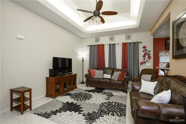 tiled living room featuring ceiling fan and a tray ceiling