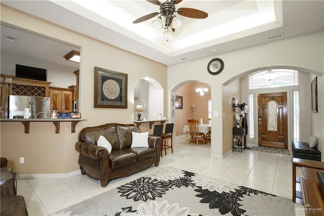 living room with ceiling fan, light tile patterned floors, and a tray ceiling