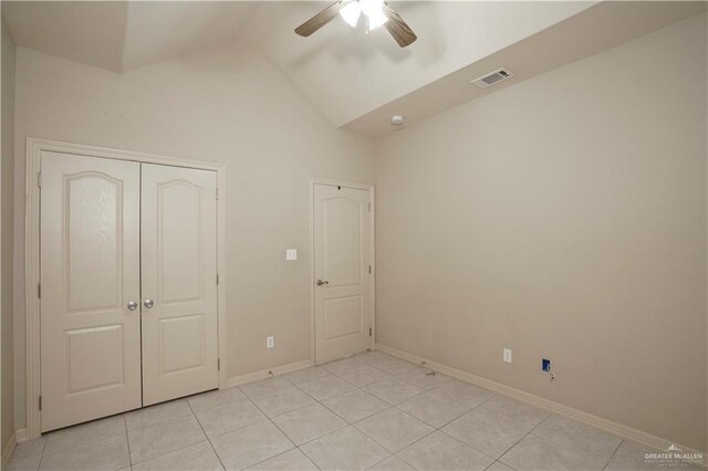 unfurnished bedroom featuring ceiling fan, a closet, light tile patterned flooring, and lofted ceiling