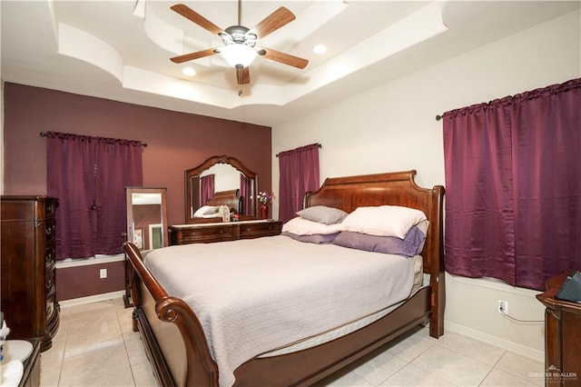 tiled bedroom featuring a raised ceiling and ceiling fan