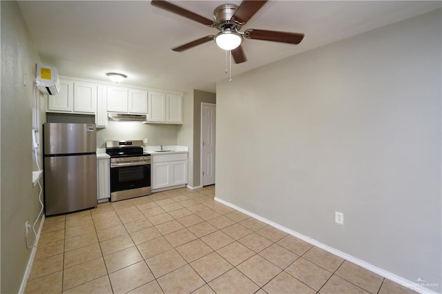 kitchen with light tile patterned flooring, a wall unit AC, ceiling fan, stainless steel appliances, and white cabinets