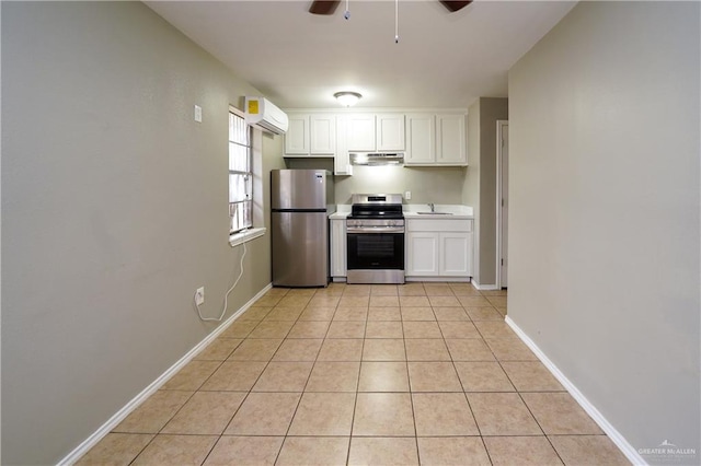 kitchen with appliances with stainless steel finishes, sink, white cabinets, light tile patterned floors, and a wall unit AC