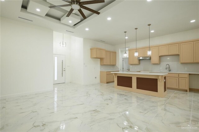 kitchen with light countertops, ceiling fan, light brown cabinets, under cabinet range hood, and a center island
