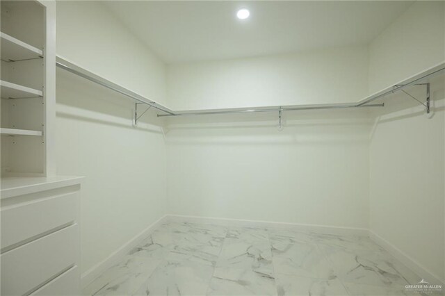 walk in closet featuring marble finish floor