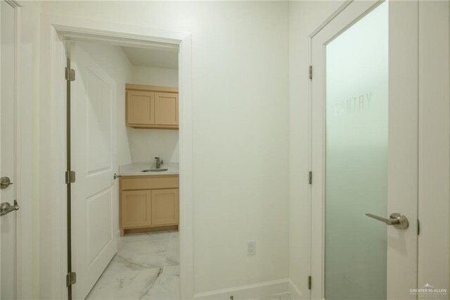 hall featuring marble finish floor and a sink