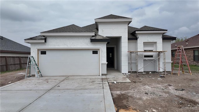 view of front of home with a garage, fence, concrete driveway, and roof with shingles