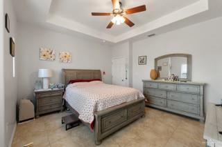 2105 Treasure Oaks Dr, Harlingen, TX 78550 - bedroom with a raised ceiling, light tile patterned flooring, and a ceiling fan
