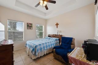 2105 Treasure Oaks Dr, Harlingen, TX 78550 - bedroom with multiple windows, light tile patterned flooring, a raised ceiling, and a ceiling fan