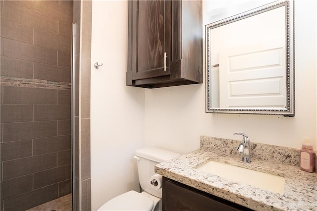 bathroom featuring vanity, toilet, and a shower with door