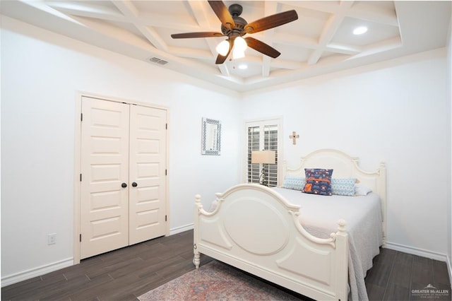 bedroom with a closet, dark hardwood / wood-style floors, ceiling fan, and coffered ceiling