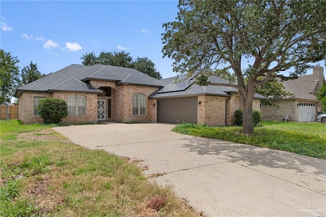 2605 Jeff St, Harlingen, TX 78550 - view of front of home with concrete driveway, a garage, solar panels, and brick siding