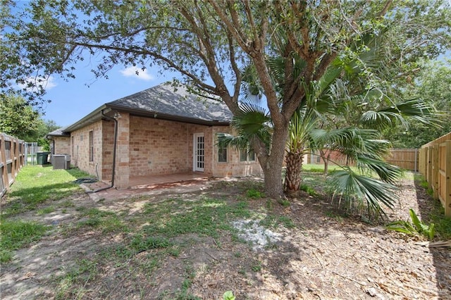 2605 Jeff St, Harlingen, TX 78550 - back of property with central AC, a fenced backyard, brick siding, a patio area, and a shingled roof