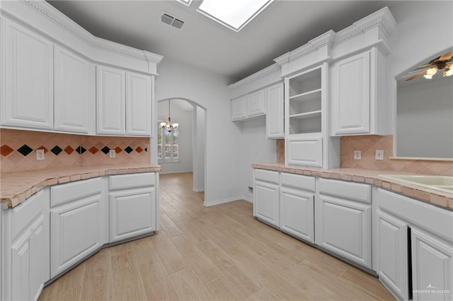 2605 Jeff St, Harlingen, TX 78550 - kitchen with arched walkways, white cabinetry, tasteful backsplash, and light wood finished floors