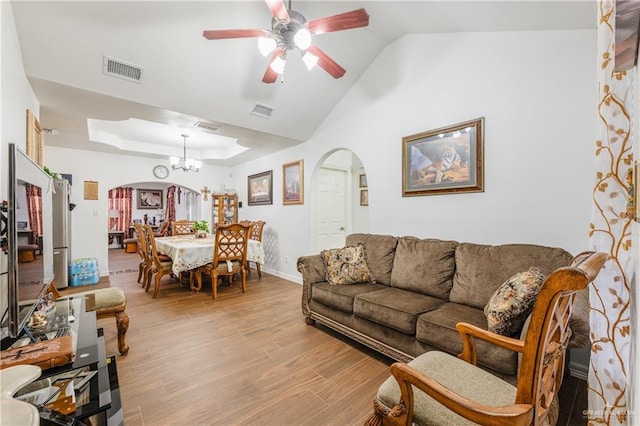 living room featuring ceiling fan with notable chandelier, vaulted ceiling, and light wood-type flooring