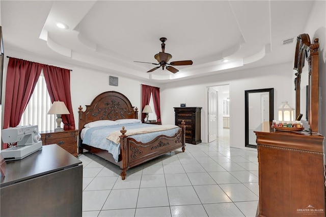 bedroom with a tray ceiling, recessed lighting, light tile patterned floors, a ceiling fan, and ensuite bath