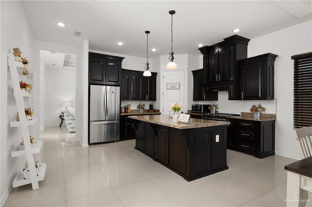 kitchen featuring stone counters, light tile patterned floors, appliances with stainless steel finishes, decorative light fixtures, and a kitchen island