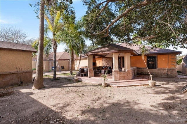 back of house with stucco siding, fence, and a patio