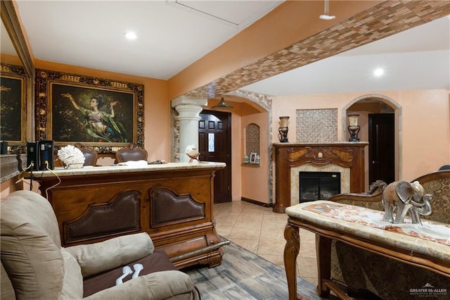 interior space with light tile patterned floors, decorative columns, arched walkways, a fireplace, and recessed lighting