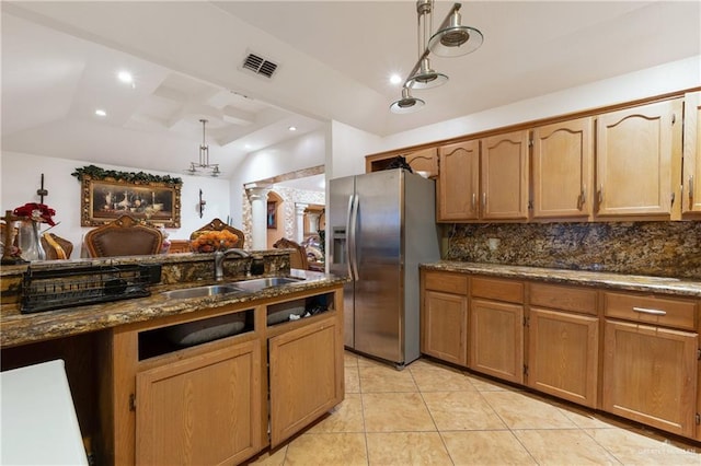 kitchen featuring tasteful backsplash, visible vents, vaulted ceiling, a sink, and stainless steel fridge