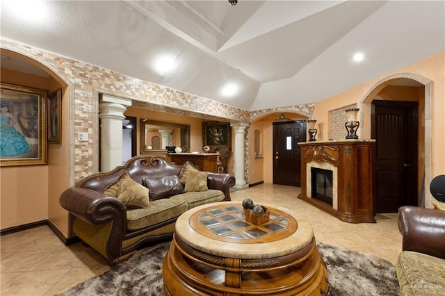 living area with arched walkways, decorative columns, lofted ceiling, a glass covered fireplace, and baseboards