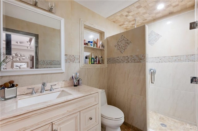 bathroom with a stall shower, toilet, tile walls, and vanity