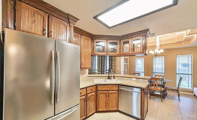 3104 Cactus Dr, Weslaco, TX 78599 - kitchen with appliances with stainless steel finishes, a sink, brown cabinetry, light tile patterned flooring, and a peninsula