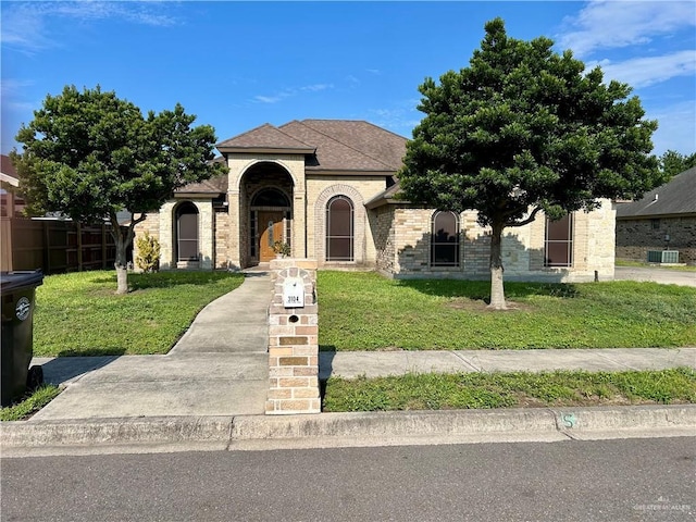 3104 Cactus Dr, Weslaco, TX 78599 - view of front of home with a front yard, central AC unit, brick siding, and a shingled roof
