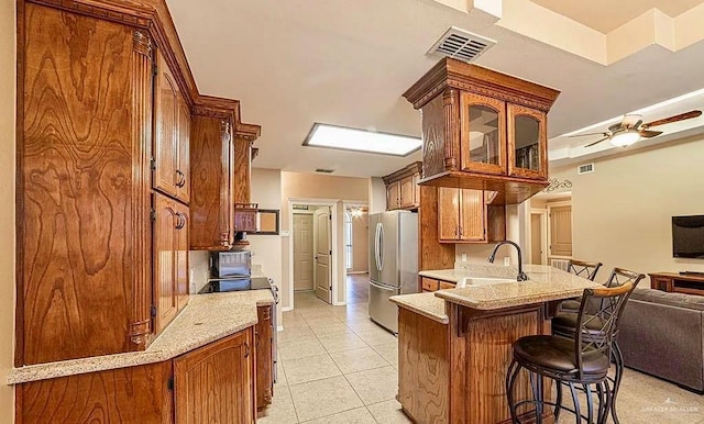 3104 Cactus Dr, Weslaco, TX 78599 - kitchen with appliances with stainless steel finishes, a sink, a peninsula, a breakfast bar area, and glass insert cabinets