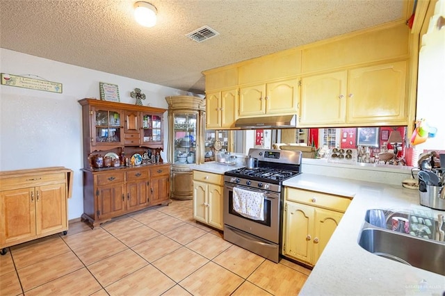 3008 W 45th St, Mission, TX 78574 - kitchen featuring stainless steel range with gas cooktop, under cabinet range hood, light countertops, light tile patterned floors, and a textured ceiling