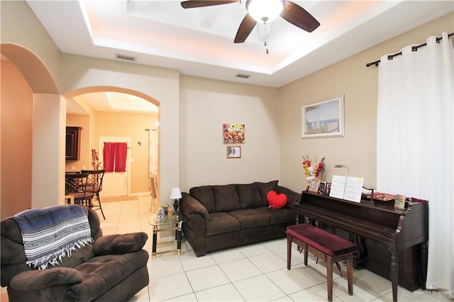 living room featuring ceiling fan, a raised ceiling, and light tile patterned floors