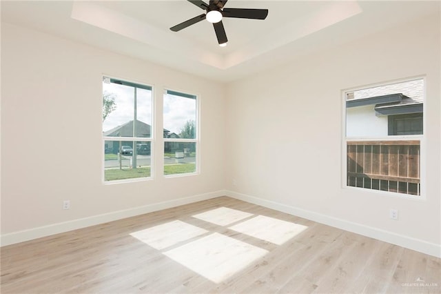 unfurnished room featuring ceiling fan, a tray ceiling, and light hardwood / wood-style floors