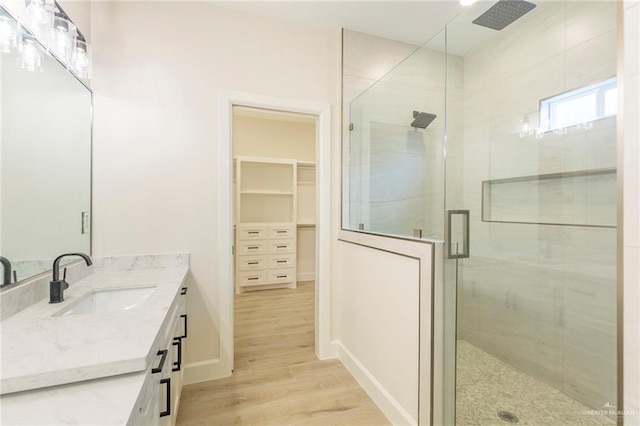 bathroom with hardwood / wood-style flooring, walk in shower, and vanity