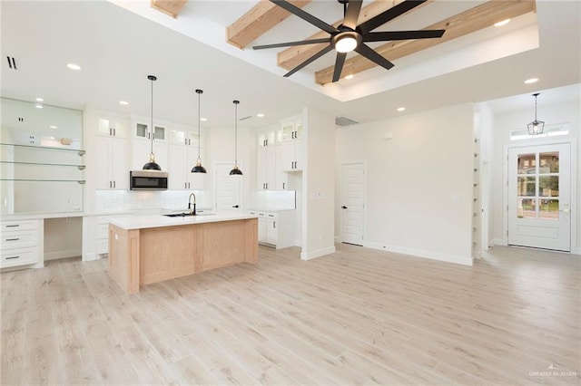 kitchen with a large island with sink, white cabinets, sink, and light hardwood / wood-style floors