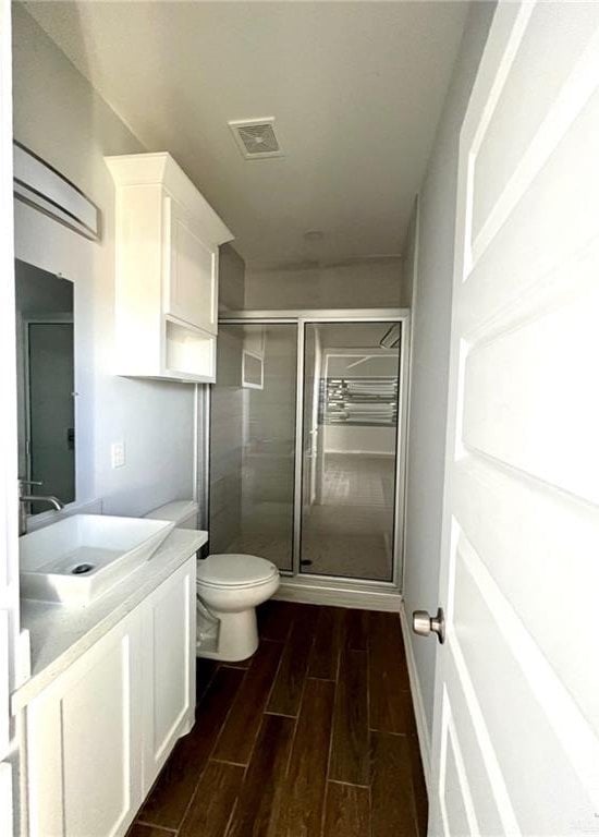 bathroom featuring vanity, toilet, and a shower with door