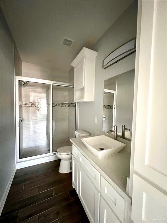 bathroom with toilet, walk in shower, and vanity