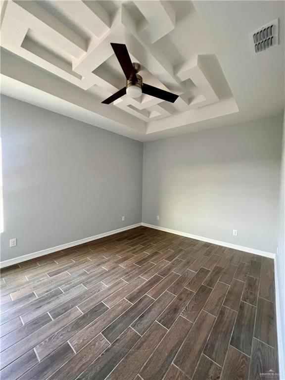 unfurnished room featuring coffered ceiling, a tray ceiling, and ceiling fan