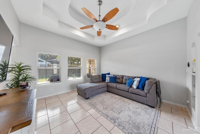 living room featuring a tray ceiling, ceiling fan, and light tile patterned flooring