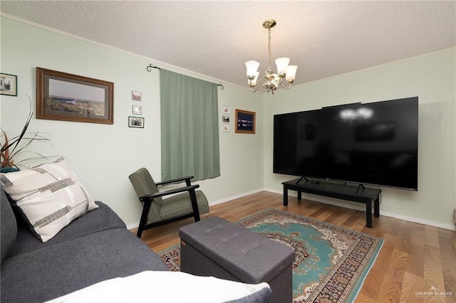 living room featuring hardwood / wood-style floors, ornamental molding, a textured ceiling, and a notable chandelier