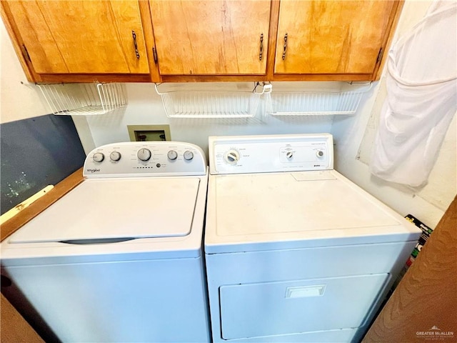 clothes washing area featuring washer and clothes dryer and cabinets