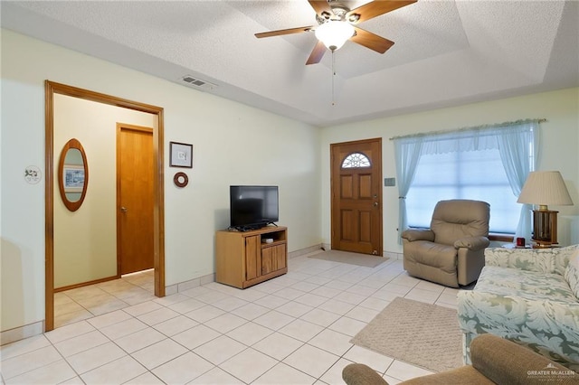 tiled living room featuring ceiling fan, a textured ceiling, and a tray ceiling