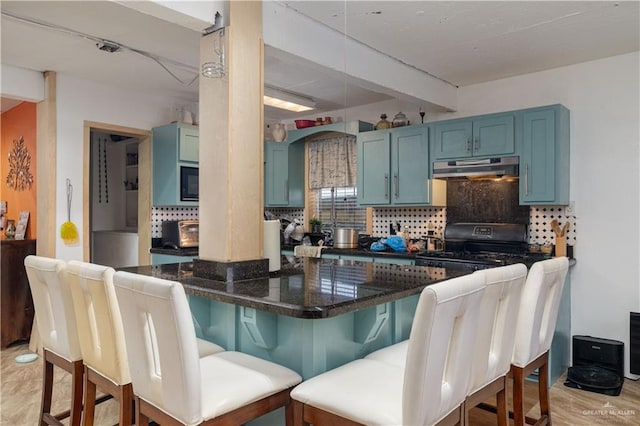 kitchen with kitchen peninsula, backsplash, a breakfast bar, black appliances, and light hardwood / wood-style floors