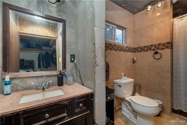 bathroom with tile patterned flooring, vanity, toilet, and tile walls