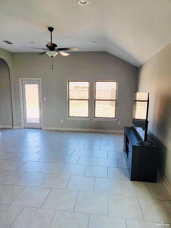 unfurnished living room featuring ceiling fan, light tile patterned floors, and vaulted ceiling